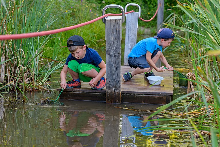 Kinder erkunden die Wasseroberfläche auf einem Floß