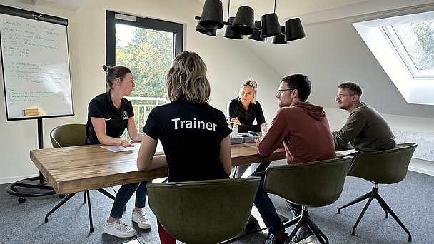 JobQuesterin Pia an einem Tisch mit Mitarbeitern von ProPhysio