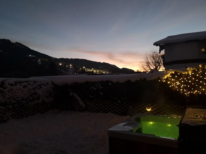 Whirlpool mit Blick auf beleuchtete Skipiste