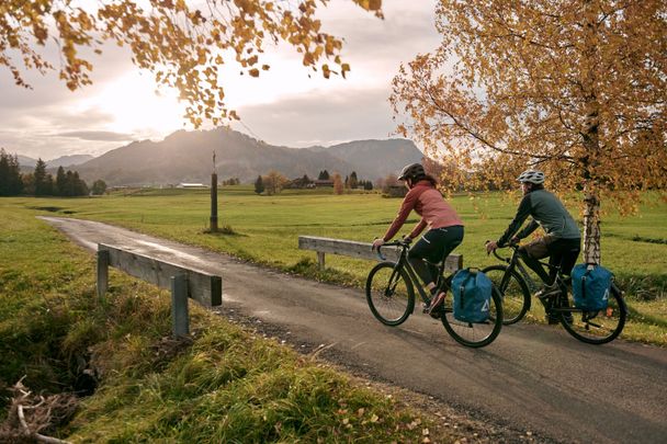 Paar radelt über Brücke in Herbstlandschaft