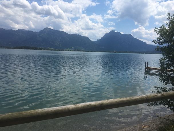 Blick entlang des Uferwegs auf den Forggensee und die Bergkette